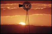 Image of burnt orange sunset behind a windmill